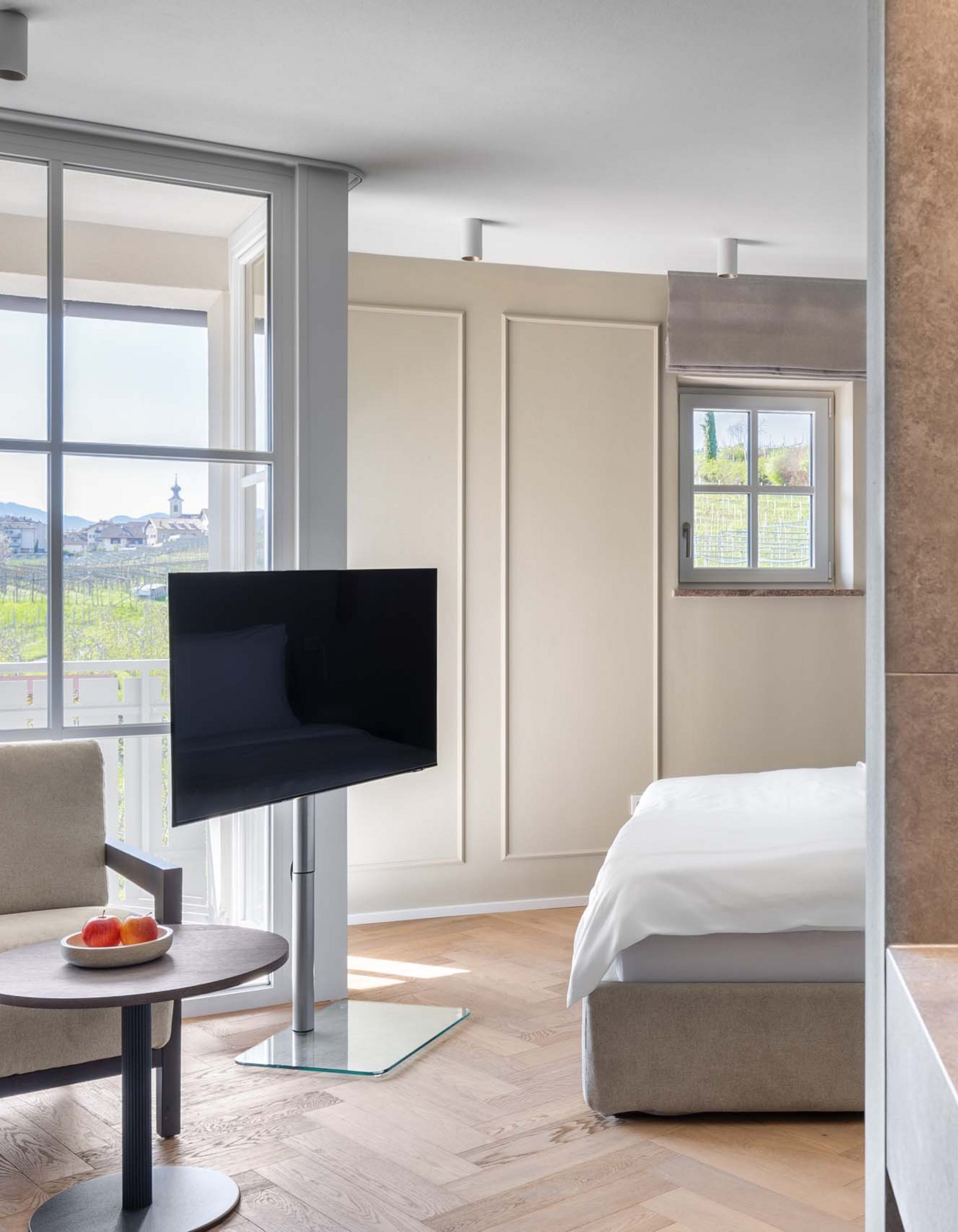 Lingers’ best snapshots Modern hotel room with armchair, TV, bed, and vineyard view through large windows