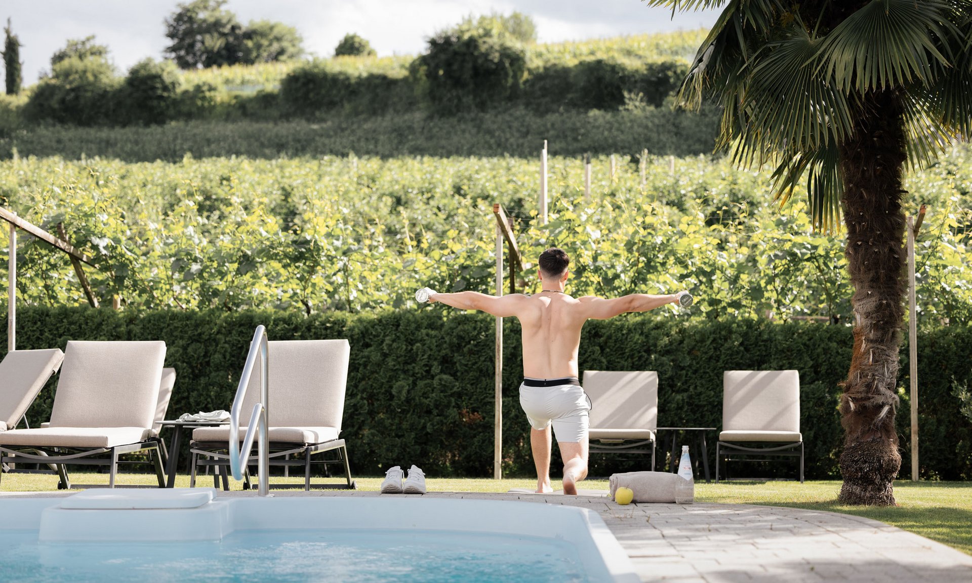 Lingers’ best snapshots Man exercising with dumbbells next to a pool in a green garden setting.