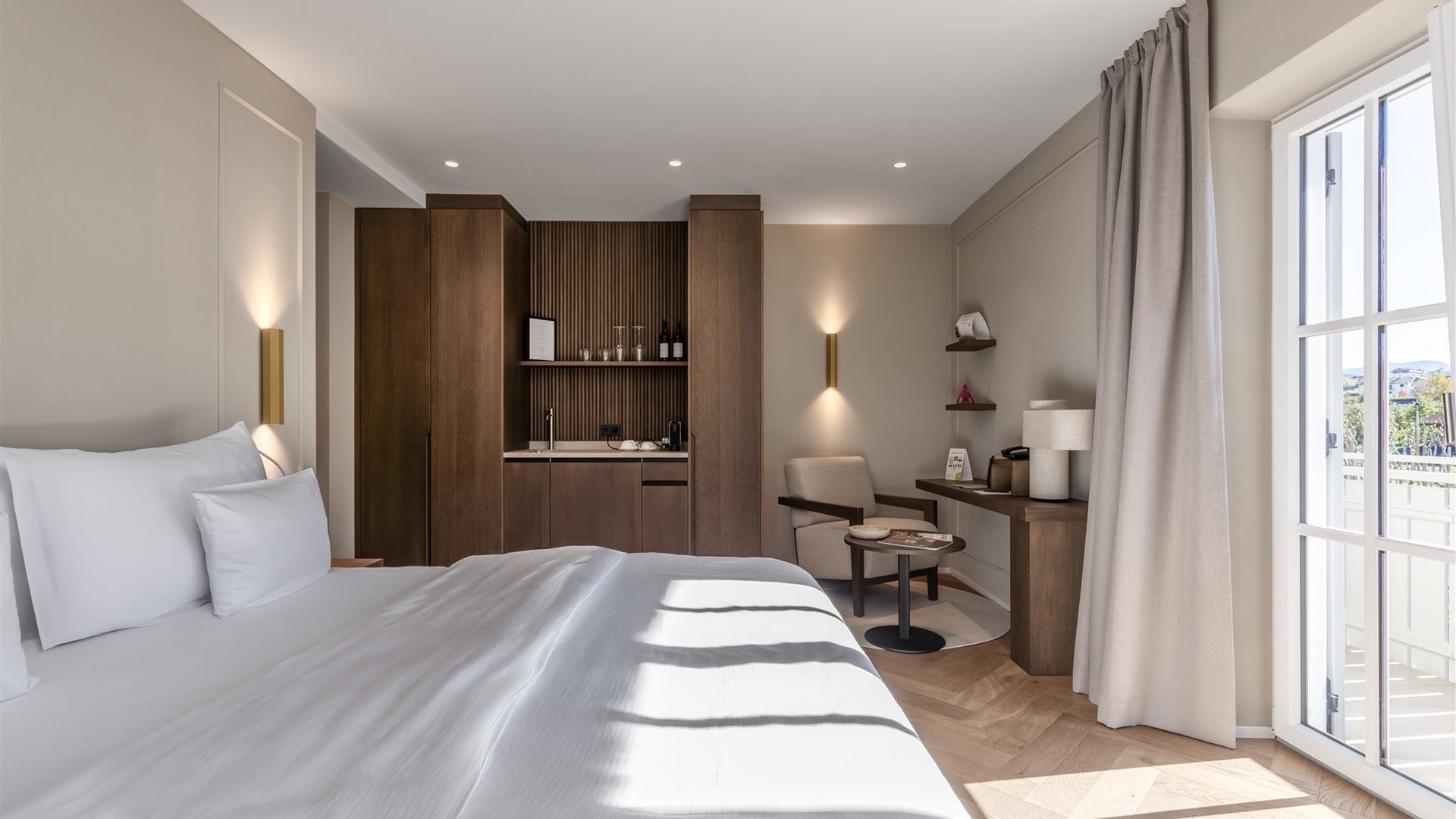 Lingers – Ihr Hotel in Girlan Helles Hotelzimmer mit großem Bett, Sessel, Schreibtisch und Balkon