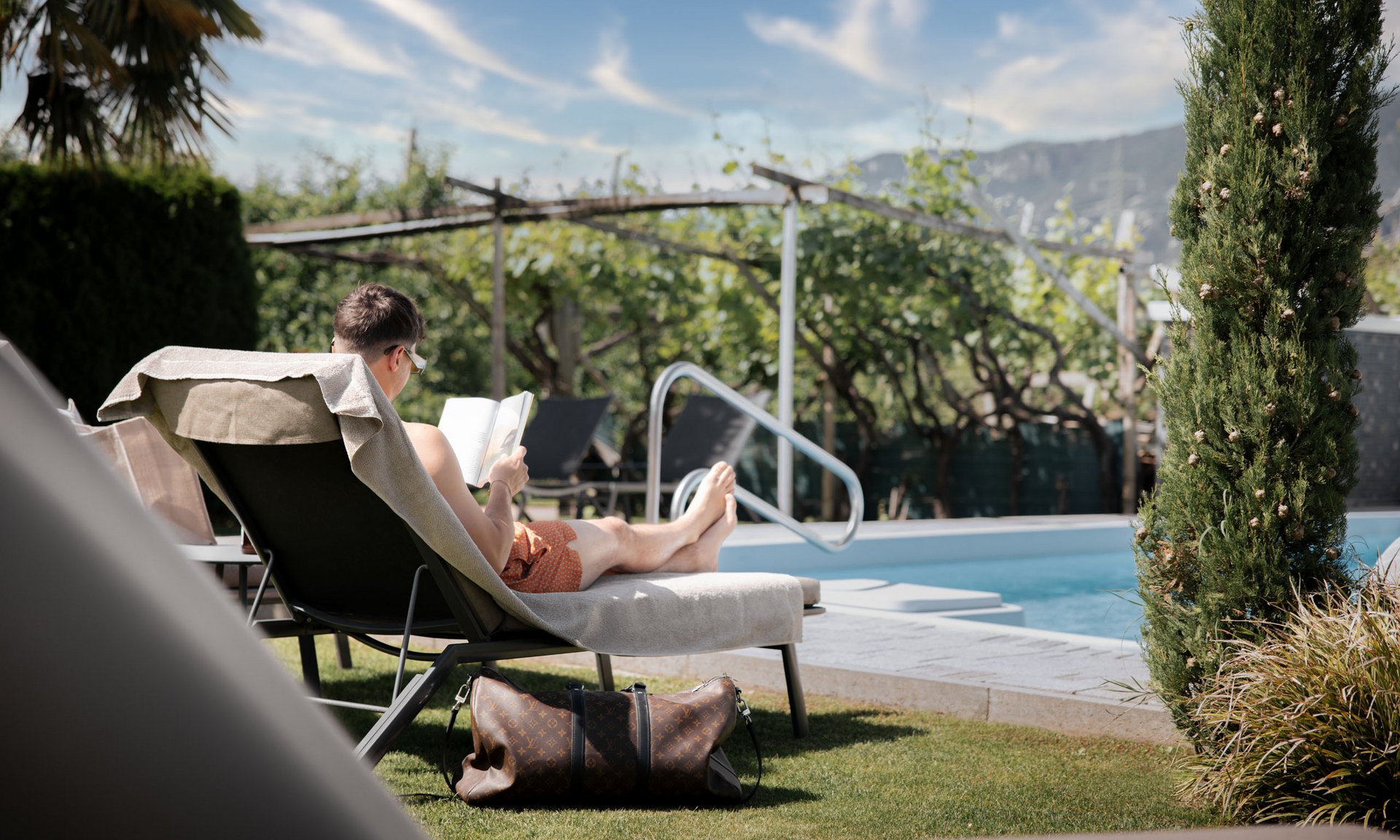 Lingers’ best snapshots Man reading on lounge chair next to pool on sunny day