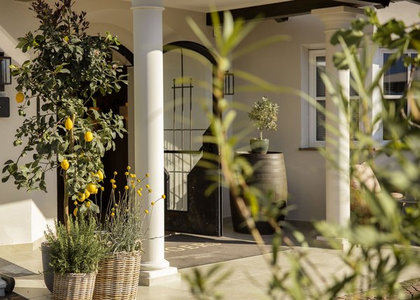 Lingers – Ihr Hotel in Girlan Eingang mit blühenden Pflanzen und Zitronen in Körben an Säulen