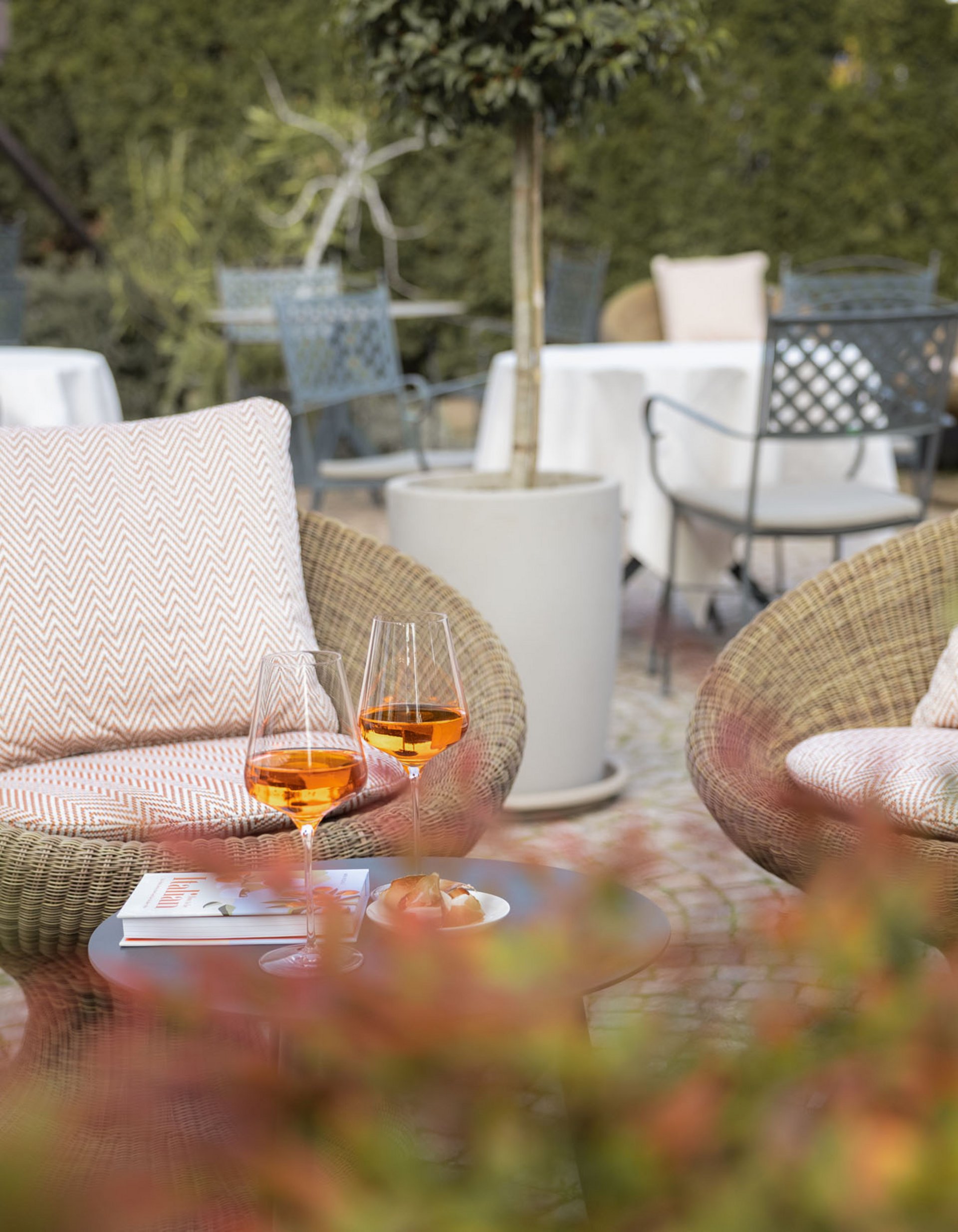 Lingers’ best snapshots Two cozy rattan chairs with drinks and snacks on a small table in a garden