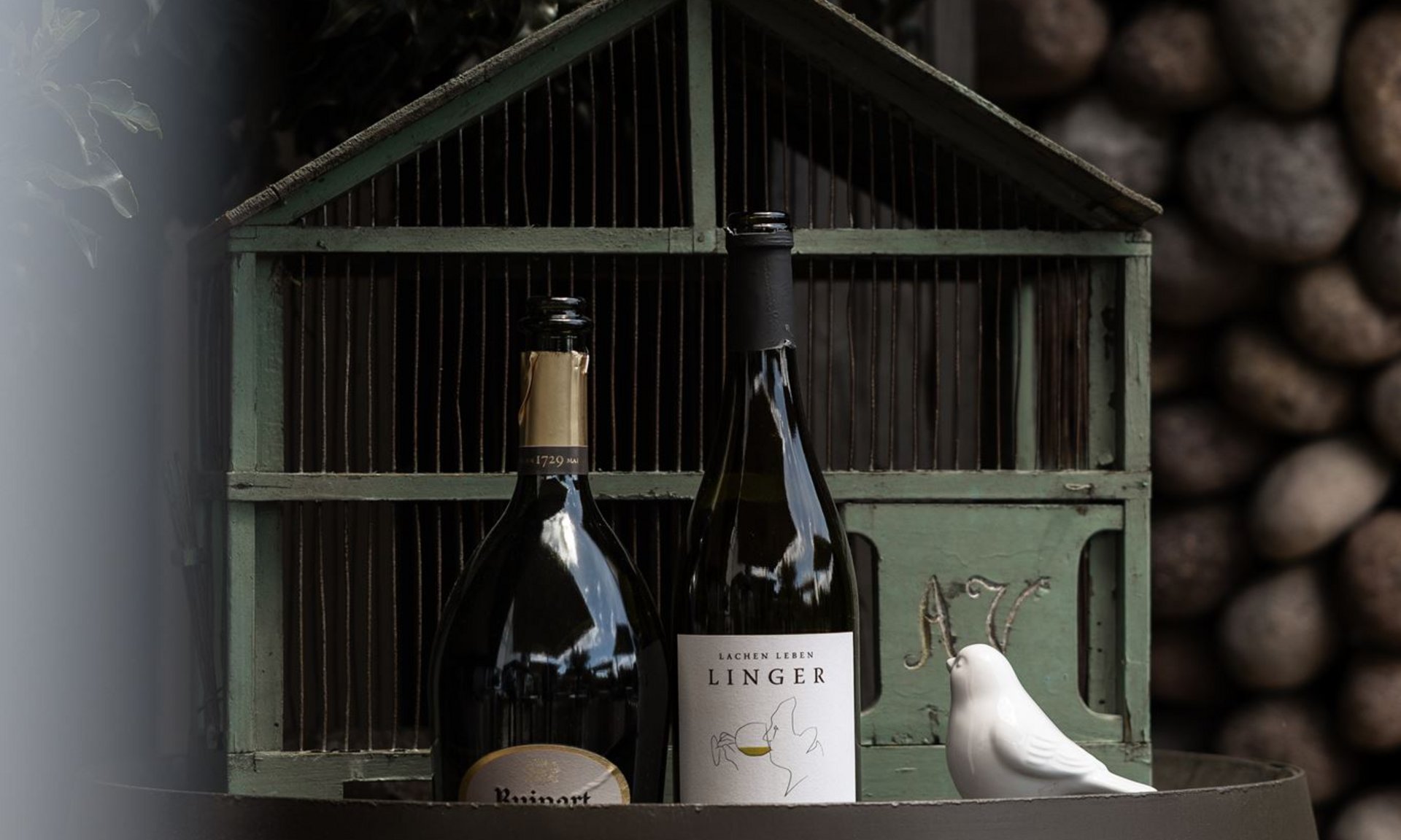 Lingers’ best snapshots Two wine bottles on a barrel in front of a birdcage with white bird statues
