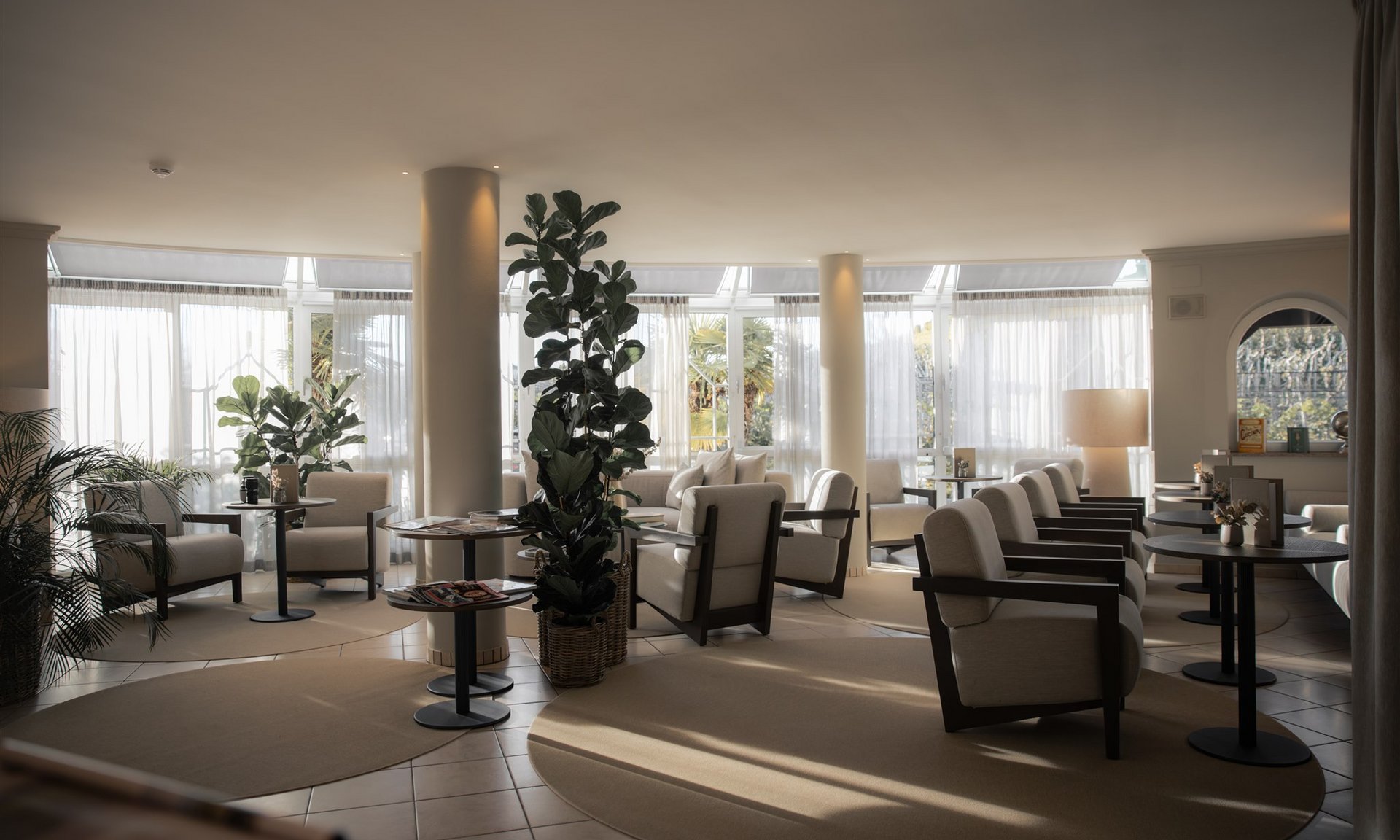 Lingers’ best snapshots Bright waiting area with armchairs, tables, and plants by large windows