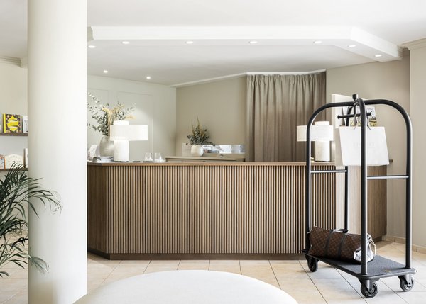 Lingers – Ihr Hotel in Girlan Moderner Hotellobby-Empfang mit Gepäckwagen und Dekoartikel