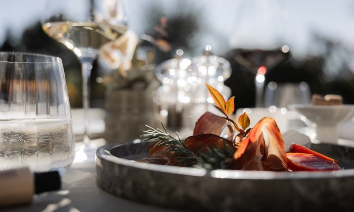 Lingers – Ihr Hotel in Girlan Antipasti-Platte mit Schinken, Tomaten und Kräutern bei Sonnenlicht