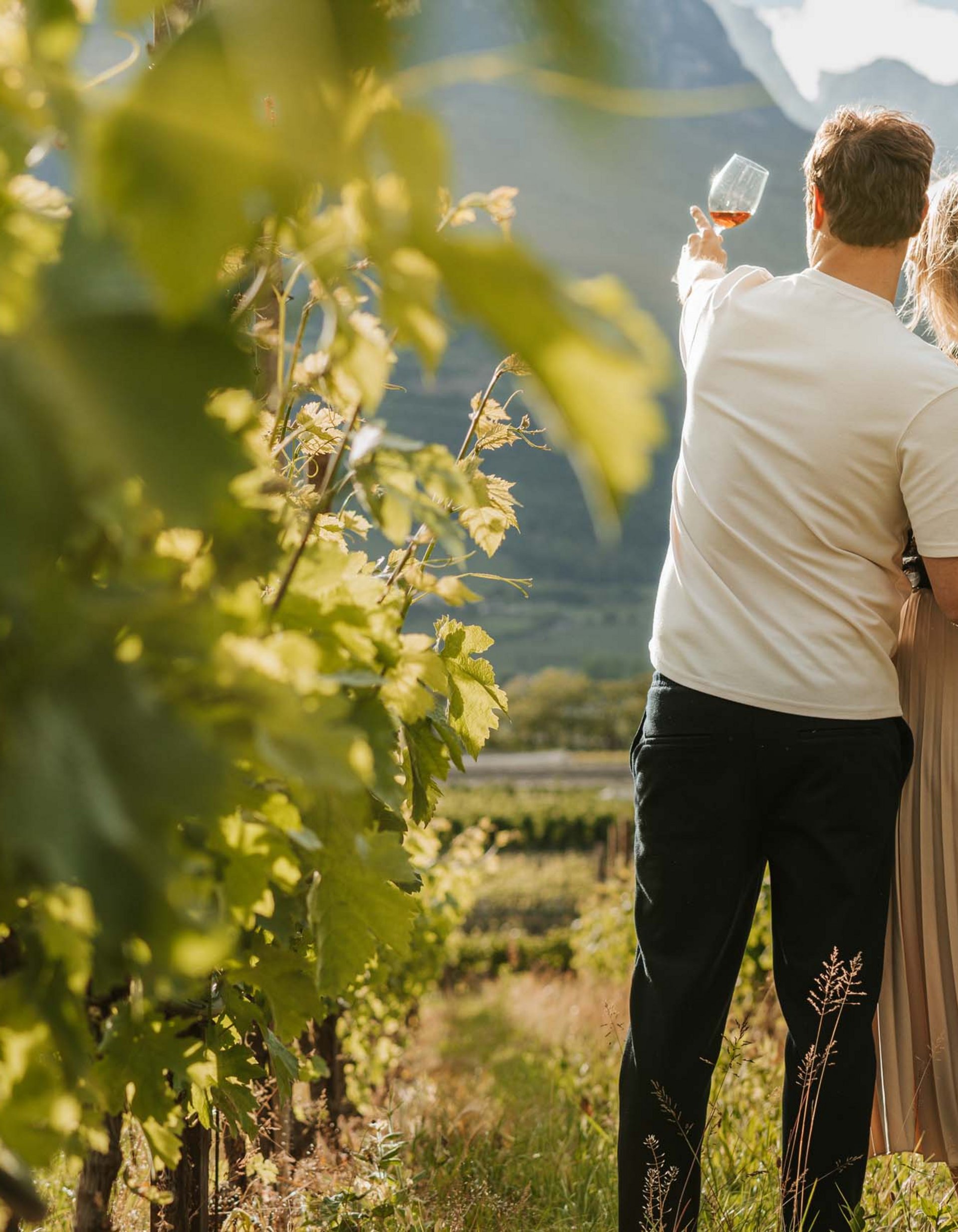 Lingers’ best snapshots Couple in vineyard, man holding wine glass pointing at mountains