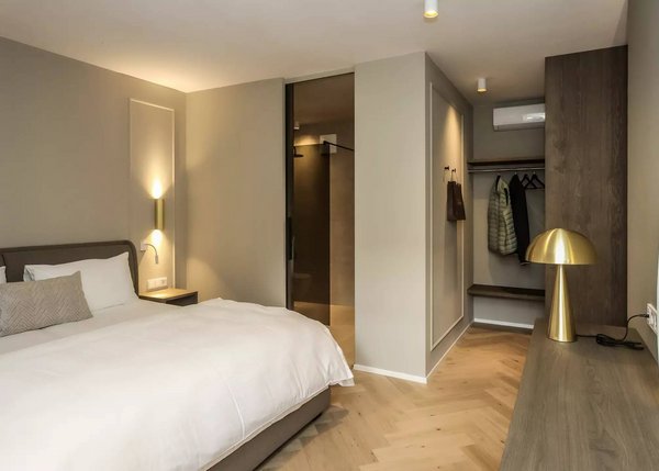 Lingers – Ihr Hotel in Girlan Modernes Schlafzimmer mit Doppelbett, Ankleide und goldener Tischlampe