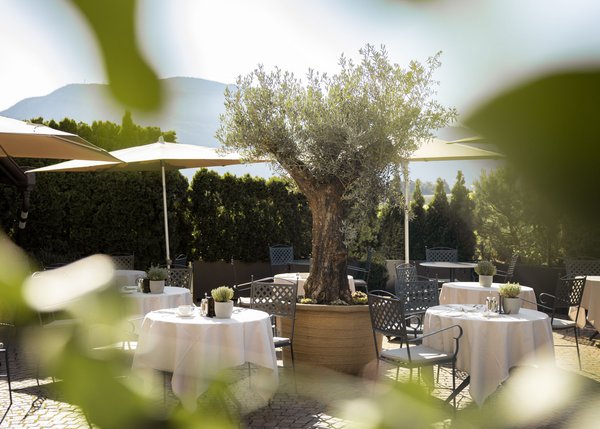 Lingers – Ihr Hotel in Girlan Sonnige Außenterrasse mit Tischen, Stühlen und großen Sonnenschirmen