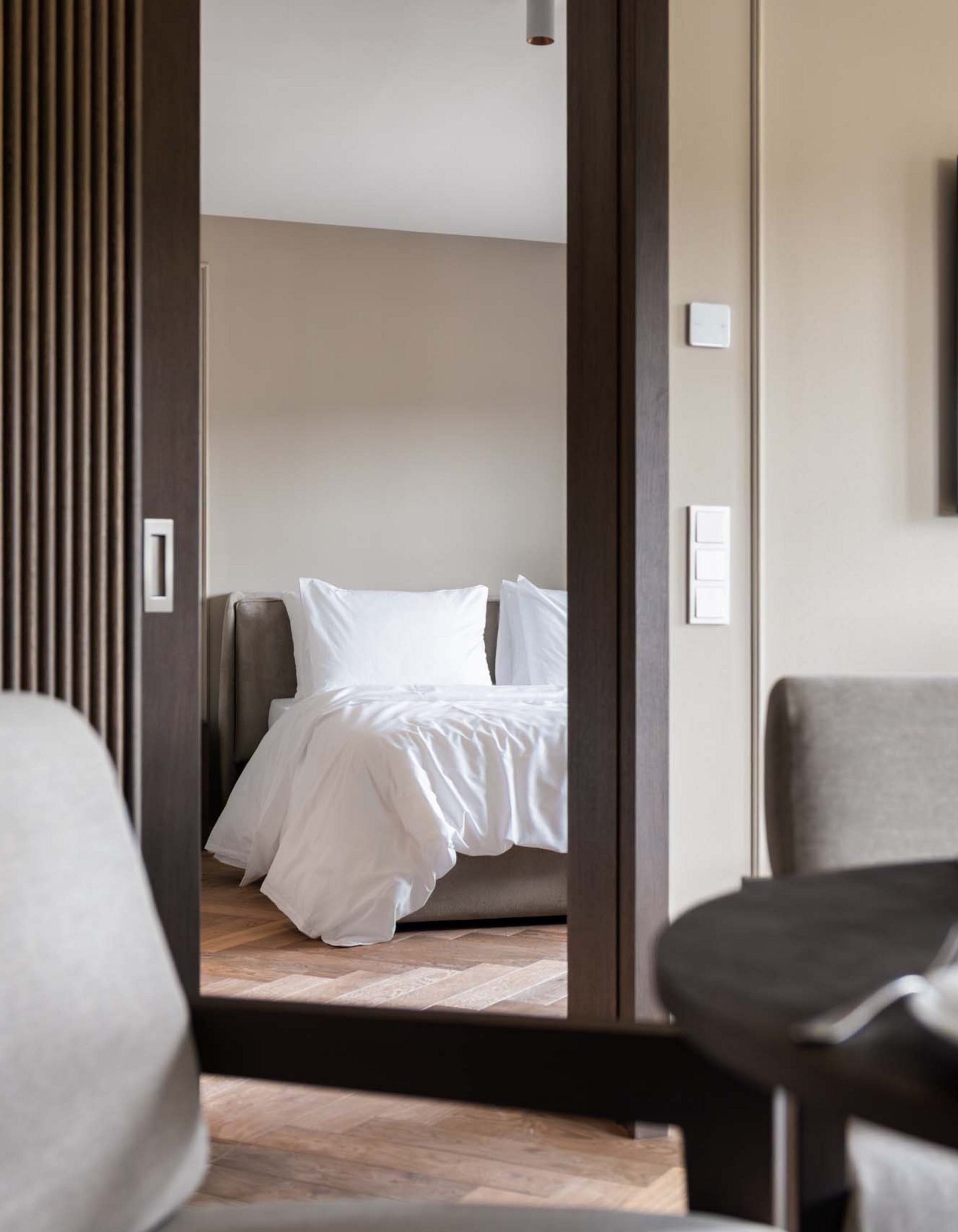 Lingers’ best snapshots View from living room to bedroom with white bed and modern TV mounted on wall